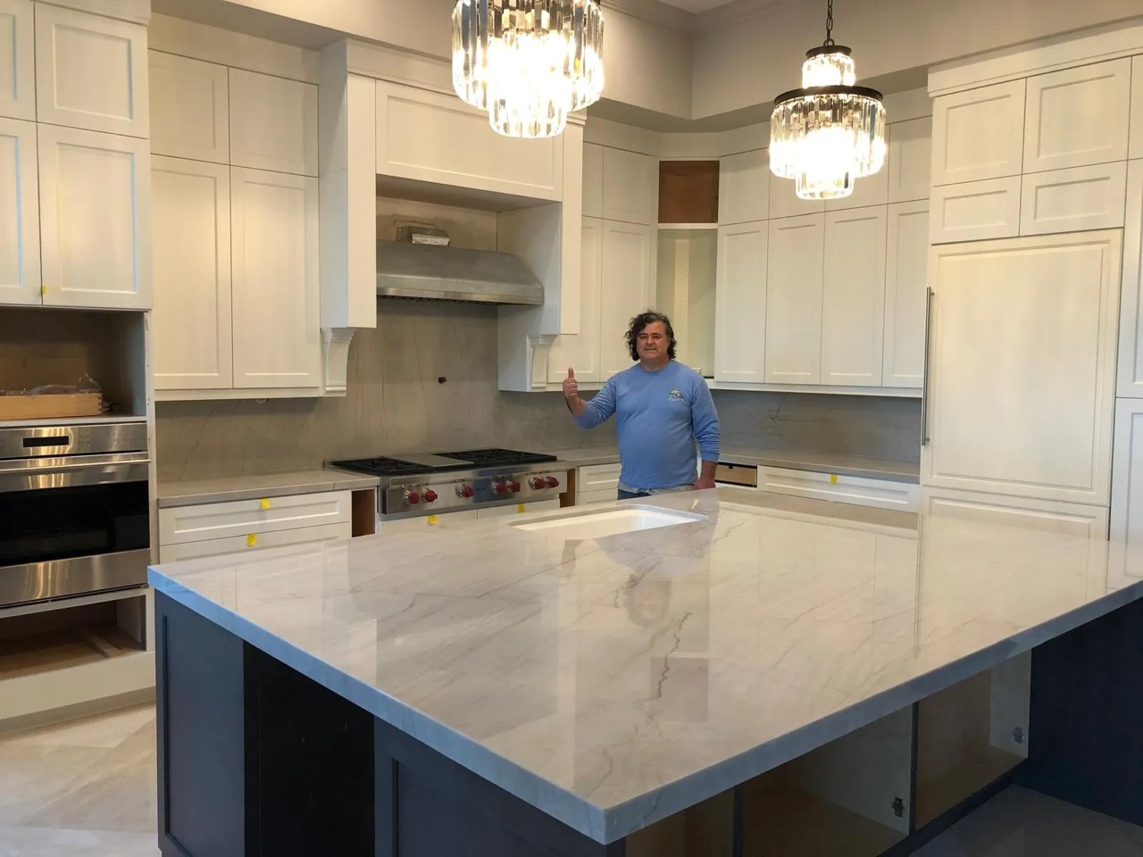 Finished white kitchen with a custom stone island by FG Custom Counters