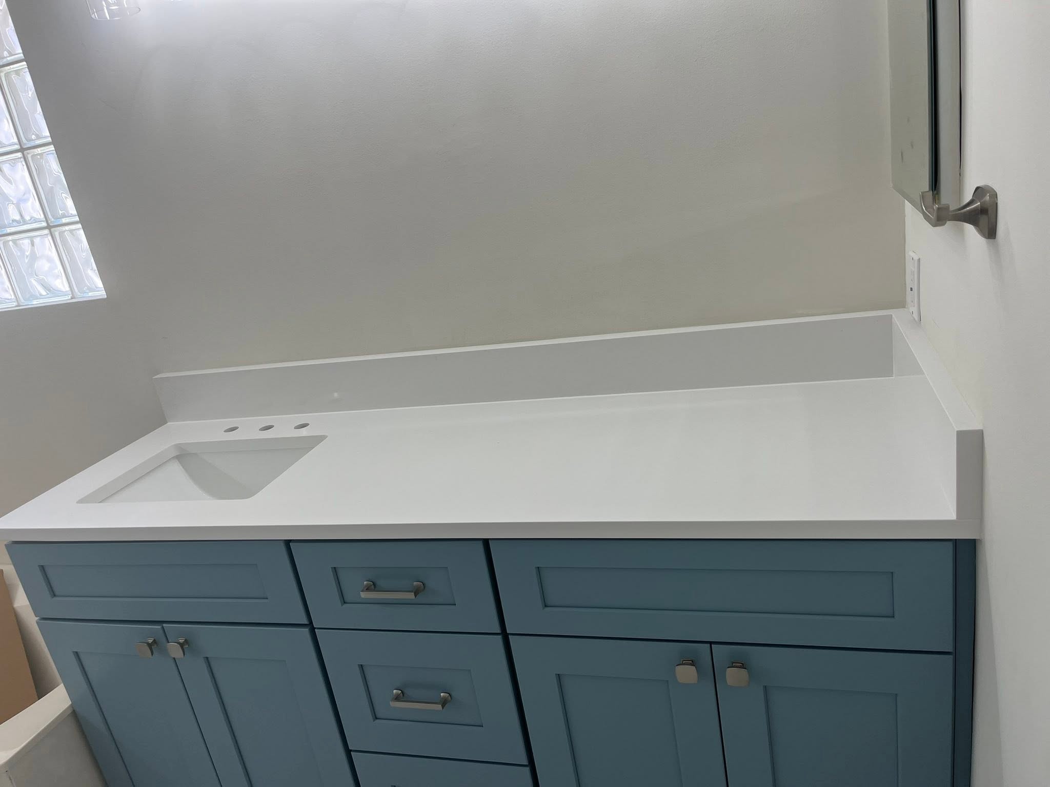 White stone countertop fitted over blue cabinets